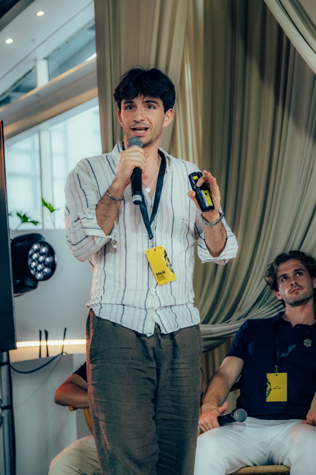 Riccardo Belli sul palco con un microfono, mentre presenta a un evento.